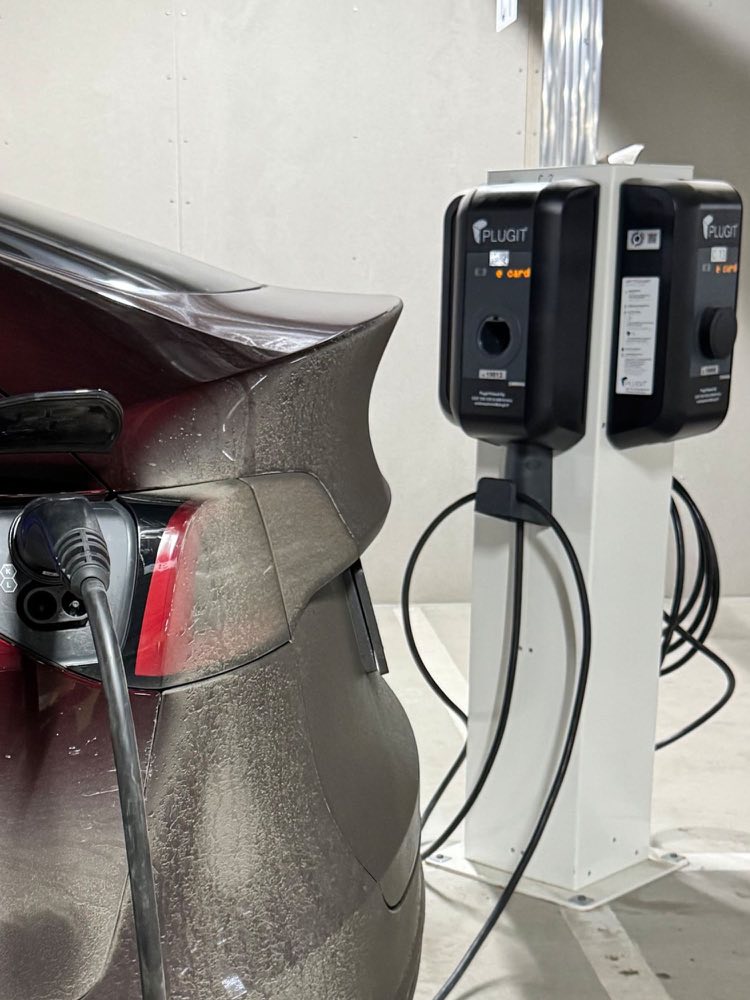 An electric car plugged into a charging post in the garage