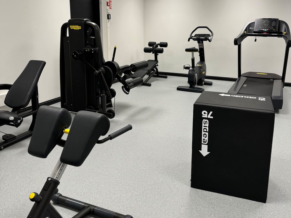 A treadmill, a stationary bike and weight-stack strength machines in the building's gym